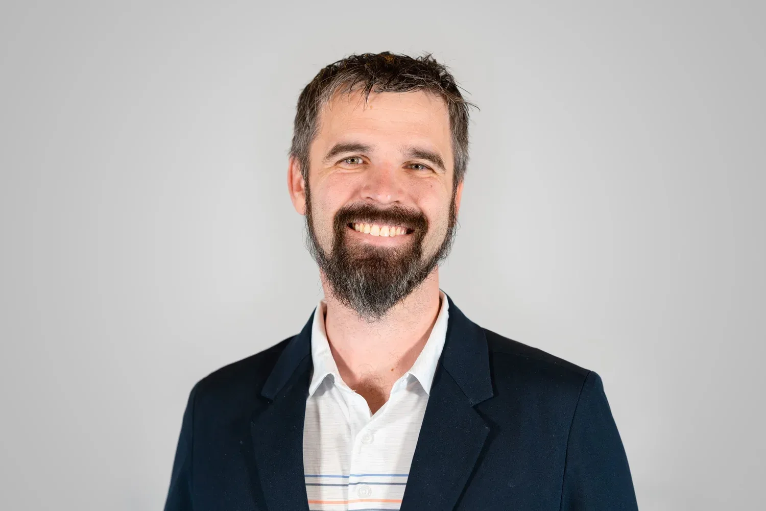 Bruce Johnson photographed on a plain backdrop with studio lighting, the setup used for team headshot days